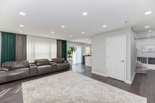 living room featuring recessed lighting, dark wood-type flooring, and stairs