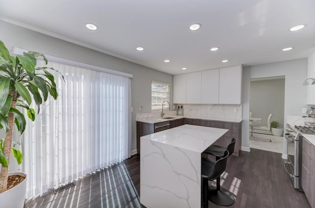 kitchen with light stone countertops, visible vents, stainless steel appliances, white cabinetry, and modern cabinets