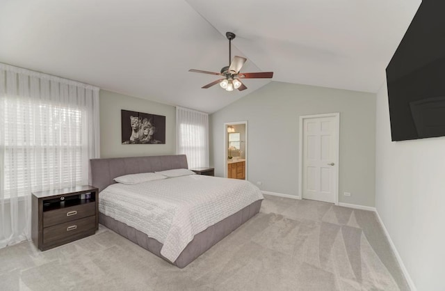 bedroom with baseboards, light colored carpet, vaulted ceiling, ensuite bathroom, and a ceiling fan