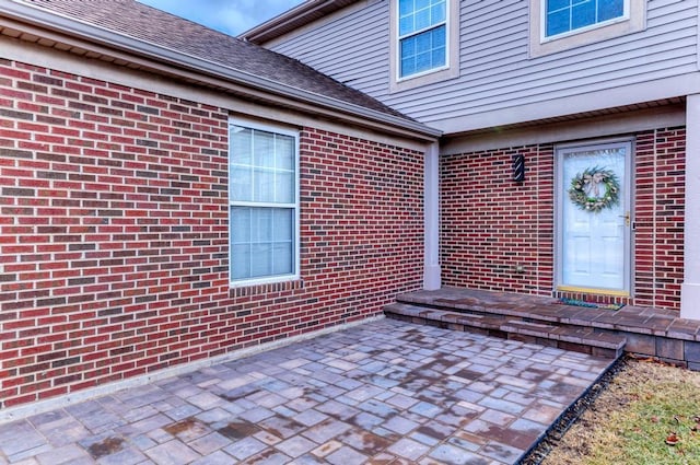 property entrance featuring brick siding and roof with shingles