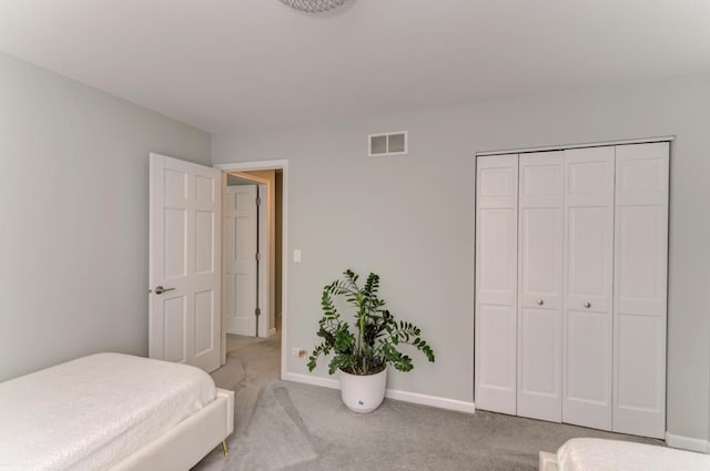 bedroom with baseboards, visible vents, a closet, and light carpet