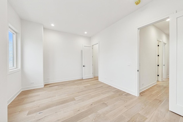 spare room featuring light wood finished floors, recessed lighting, and baseboards