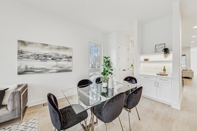 dining space with light wood finished floors and baseboards