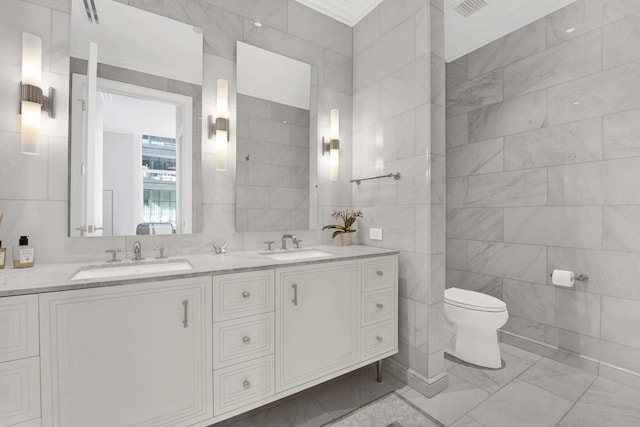 bathroom featuring double vanity, toilet, tile walls, and a sink