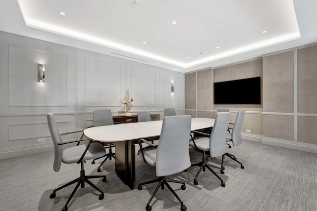 office space featuring a raised ceiling, light colored carpet, and a decorative wall