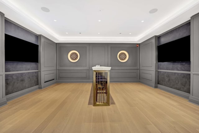 interior space featuring recessed lighting, a tray ceiling, light wood-style floors, and a decorative wall