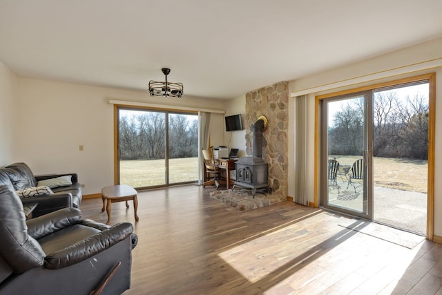 living area featuring a wood stove, wood finished floors, and a healthy amount of sunlight