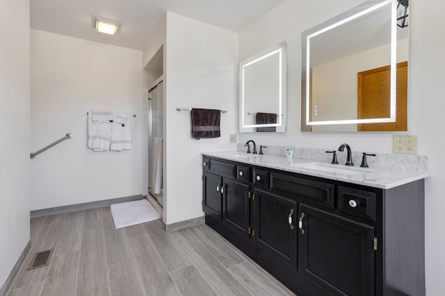 full bathroom with a stall shower, baseboards, visible vents, and a sink