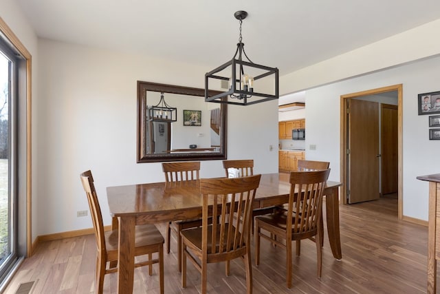 dining space featuring visible vents, baseboards, a notable chandelier, and light wood-style flooring