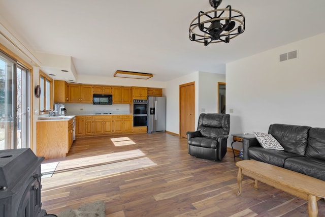 kitchen featuring visible vents, black appliances, light countertops, and open floor plan