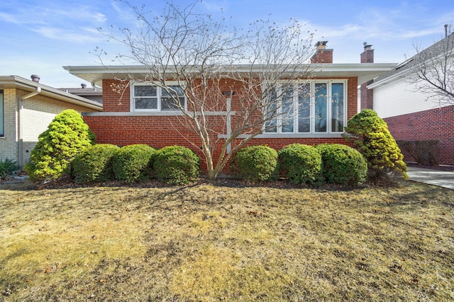 view of front of house with brick siding and a chimney