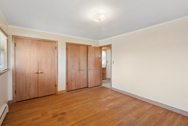 unfurnished bedroom featuring light wood finished floors, two closets, crown molding, baseboards, and a baseboard radiator