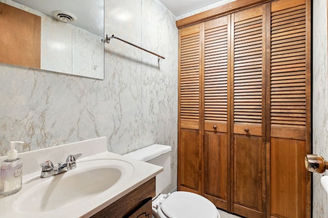 bathroom featuring a closet, visible vents, toilet, and vanity