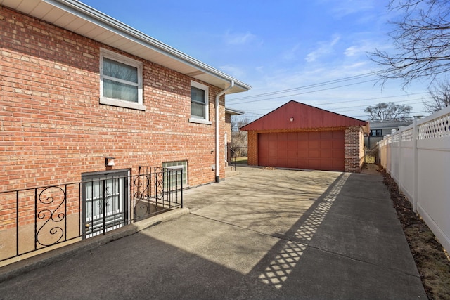 view of patio with an outbuilding, a detached garage, and fence