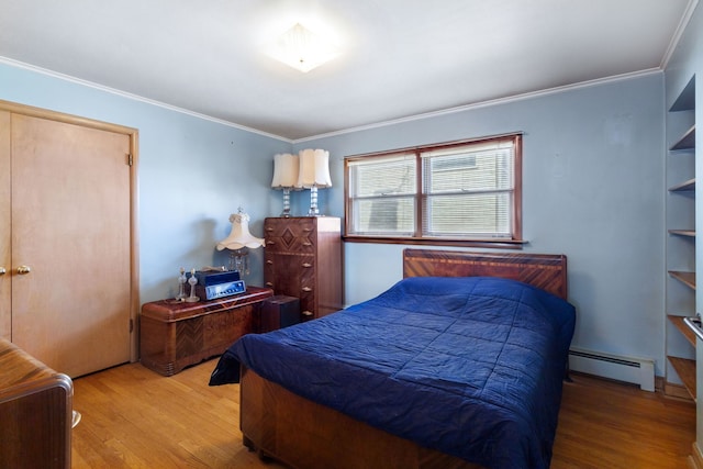 bedroom with crown molding, wood finished floors, and baseboard heating