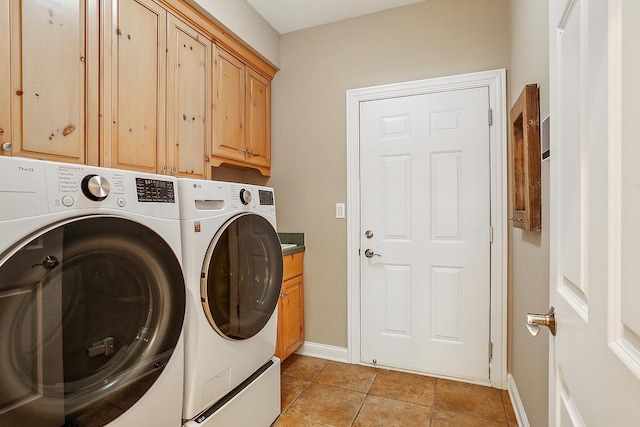 clothes washing area with baseboards, cabinet space, washing machine and dryer, and light tile patterned flooring