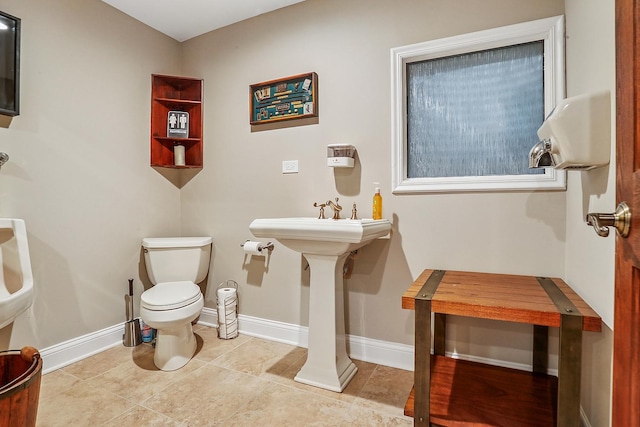 bathroom with baseboards, toilet, and tile patterned flooring