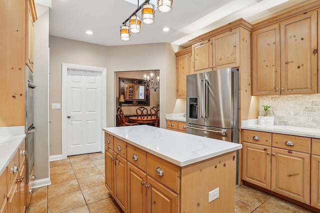 kitchen with tasteful backsplash, a kitchen island, a chandelier, light countertops, and appliances with stainless steel finishes