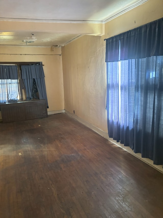 spare room featuring beamed ceiling, wood-type flooring, and baseboards