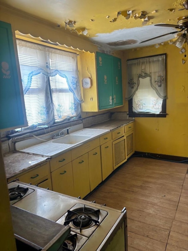 kitchen with white range with gas cooktop, light wood-type flooring, light countertops, and a sink