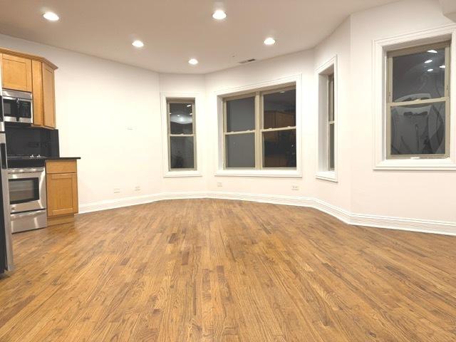 kitchen featuring brown cabinets, wood finished floors, recessed lighting, stainless steel appliances, and baseboards