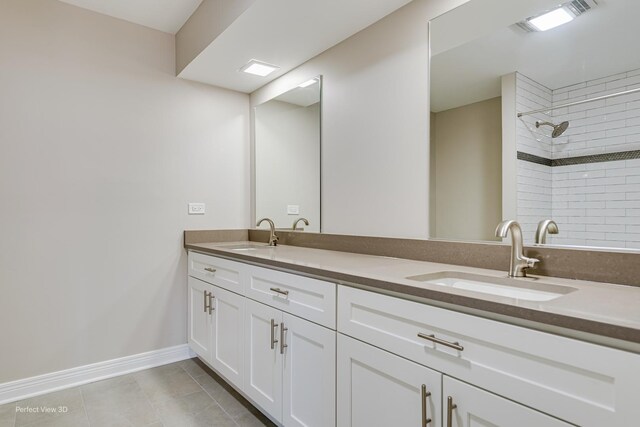 full bath featuring a sink, visible vents, tiled shower, and double vanity