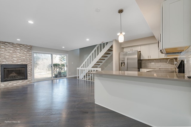 kitchen featuring tasteful backsplash, white cabinets, dark wood-style floors, stainless steel fridge, and a sink