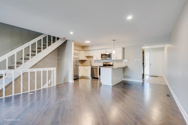 unfurnished living room featuring visible vents, dark wood-type flooring, recessed lighting, baseboards, and stairs