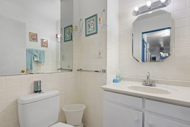 bathroom featuring toilet, tile walls, and vanity