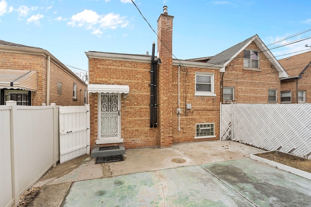 back of house featuring a patio area, fence, brick siding, and a chimney