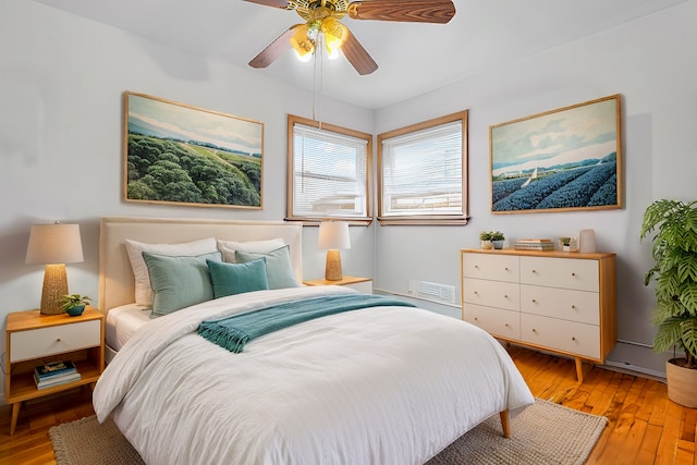 bedroom with light wood-style flooring, a ceiling fan, and visible vents