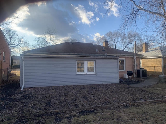 rear view of house featuring central AC unit and fence