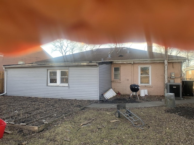 rear view of house featuring central AC unit and brick siding