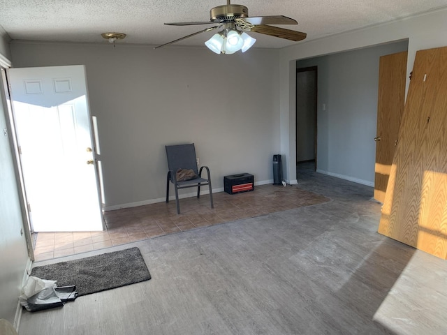 interior space featuring baseboards, a textured ceiling, and ceiling fan