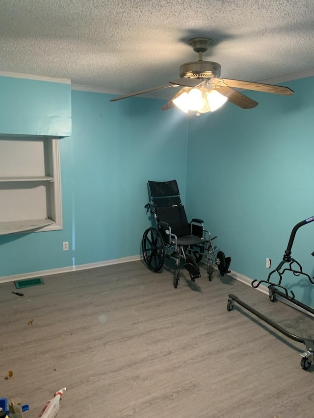 exercise room featuring visible vents, a textured ceiling, wood finished floors, and crown molding