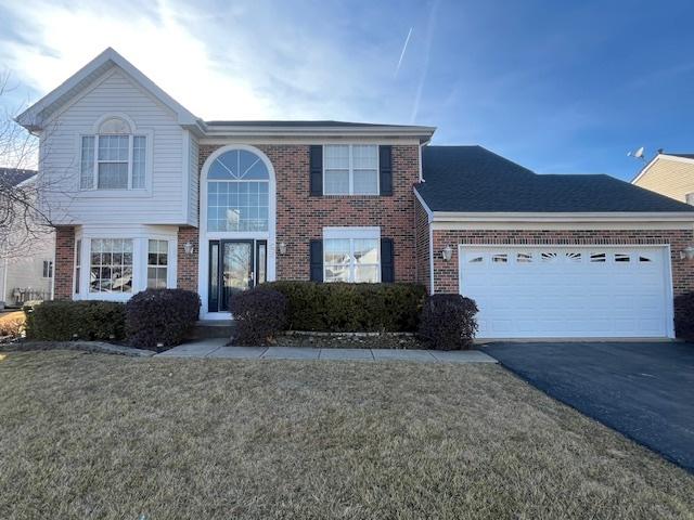 view of front of home featuring aphalt driveway, brick siding, a garage, and a front yard