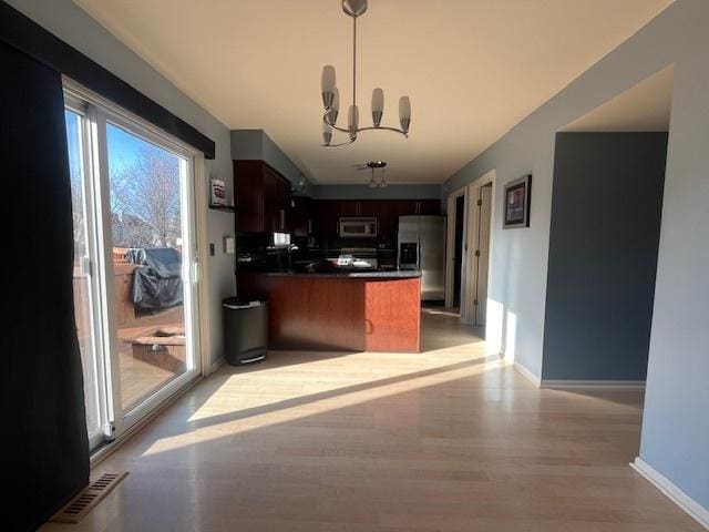 kitchen with dark countertops, visible vents, a peninsula, a notable chandelier, and stainless steel appliances