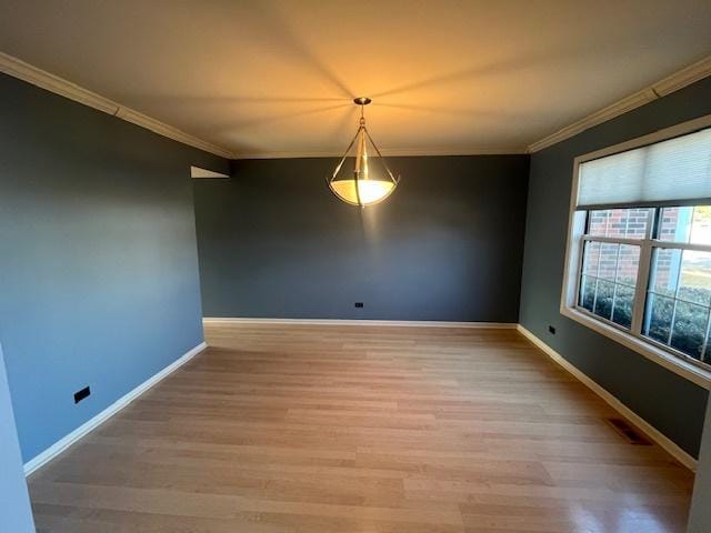 unfurnished room featuring visible vents, light wood-style flooring, baseboards, and ornamental molding