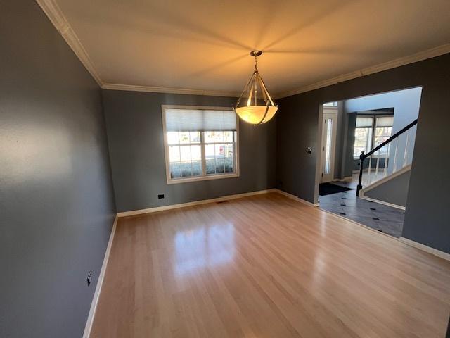 unfurnished dining area with stairs, crown molding, baseboards, and wood finished floors