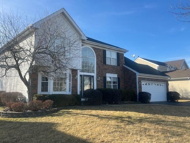 view of front of property featuring a garage, brick siding, and a front lawn