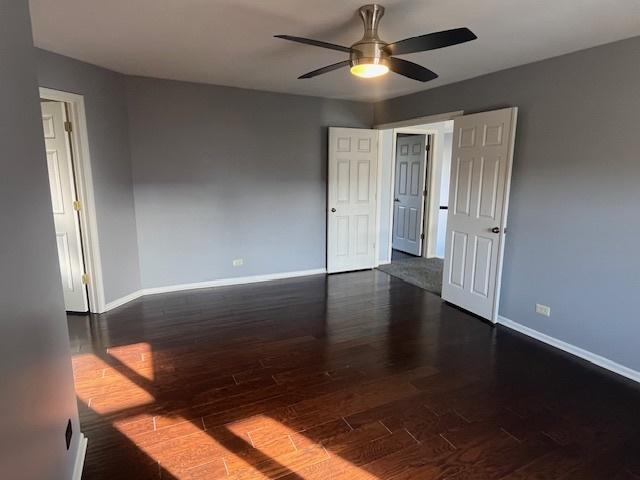 spare room featuring baseboards, ceiling fan, and dark wood-style flooring