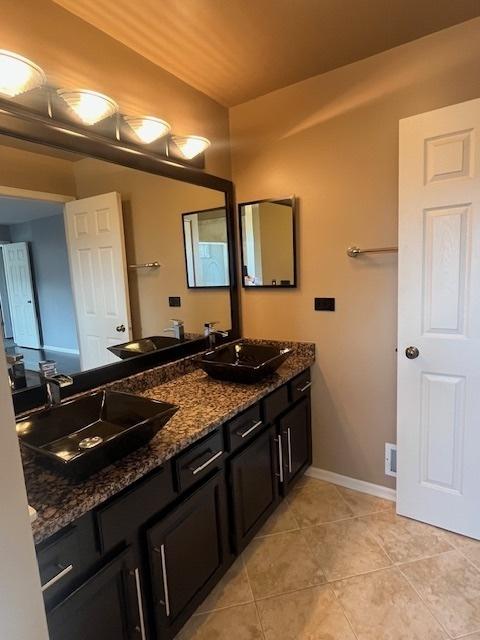 bathroom with tile patterned floors, baseboards, and a sink