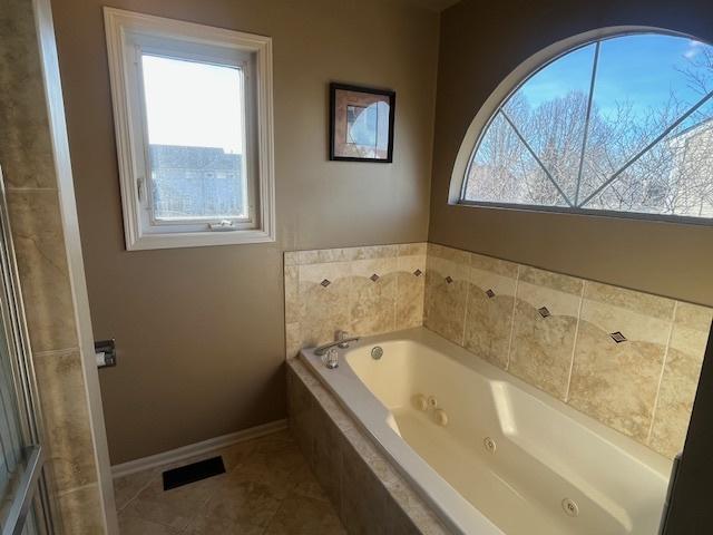 bathroom with visible vents, a healthy amount of sunlight, baseboards, and a whirlpool tub