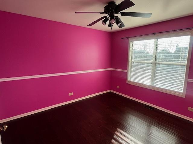 unfurnished room with visible vents, ceiling fan, baseboards, and wood finished floors