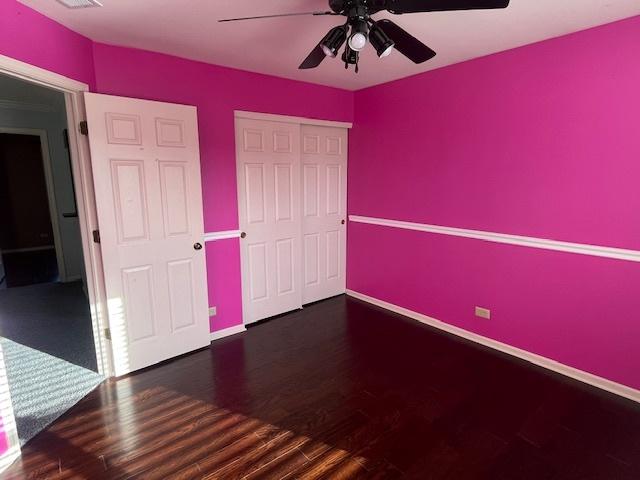 unfurnished bedroom with a closet, ceiling fan, baseboards, and wood finished floors