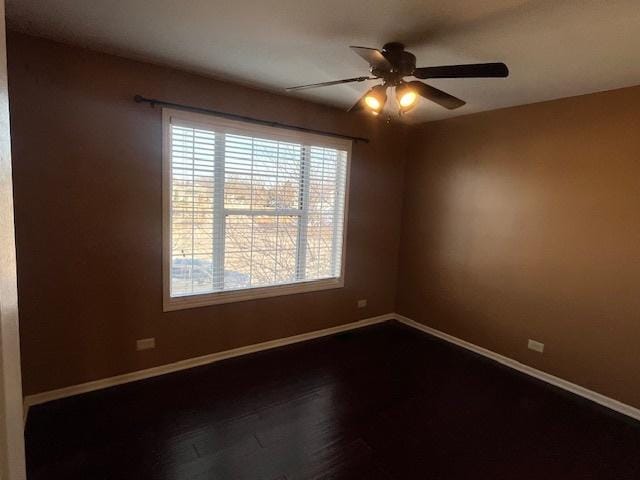 spare room featuring dark wood-style floors, baseboards, and ceiling fan