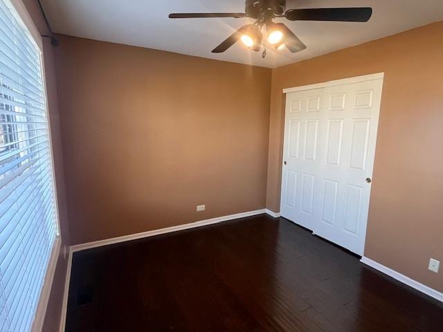 unfurnished bedroom with baseboards, dark wood finished floors, and a ceiling fan