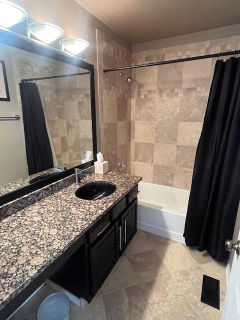 full bath featuring visible vents, vanity, and shower / tub combo