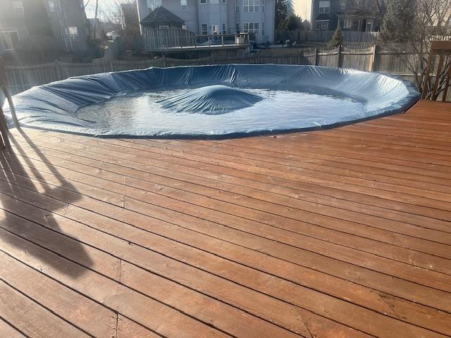 view of pool featuring a jacuzzi, a wooden deck, a covered pool, and fence