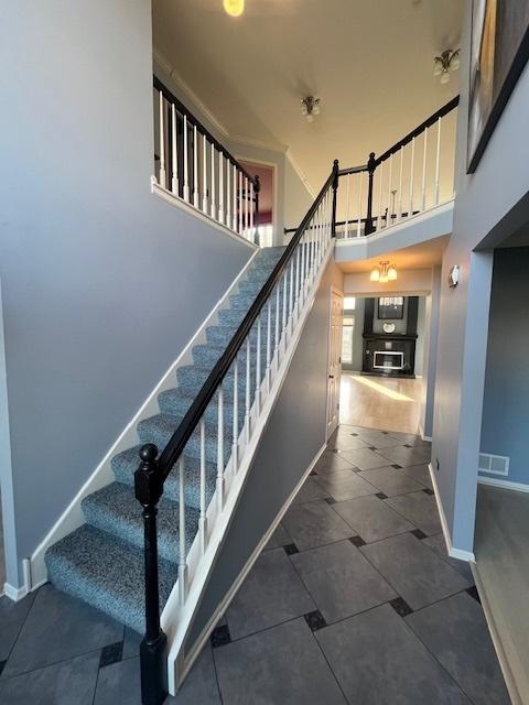 staircase featuring visible vents, baseboards, and a towering ceiling